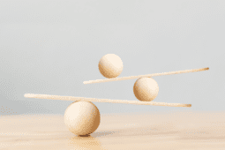 Three wooden balls balancing on wooden boards on a table.